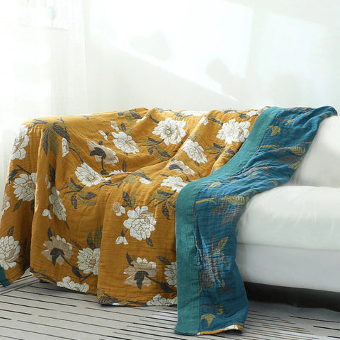 Floral-patterned quilt draped over a white sofa with Golden Bloom Cotton Throw Blanket.