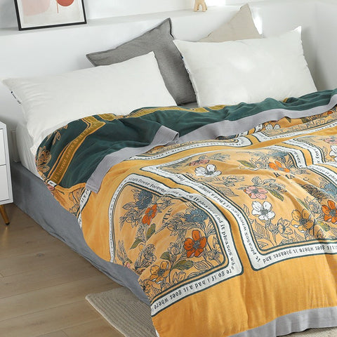 Golden Romance Boho Throw Blanket spread on a bed with white and gray pillows in a bright bedroom setting.