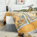 Golden Romance Boho cotton throw blanket casually draped over bed corner with decorative balls and bedside table in background.