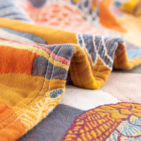 Detailed close-up of Golden Wings cotton quilt edge showing mustard yellow fabric with colorful embroidered patterns and neat stitching
