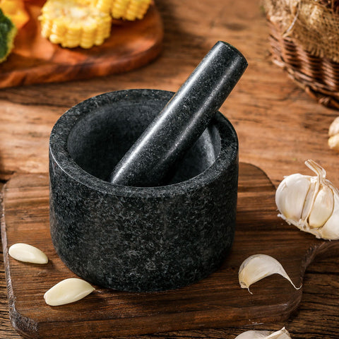 Granite mortar and pestle with fresh garlic and spices on a kitchen table