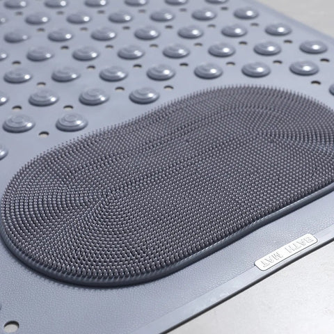 Close-up of foot scrubber texture on gray shower mat

