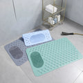 Two bath mats, one green and one gray, on a bathroom floor with a shower head and basket in the background.