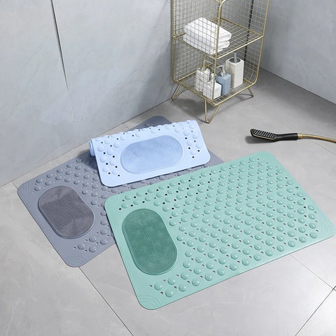 Two bath mats, one green and one gray, on a bathroom floor with a shower head and basket in the background.
