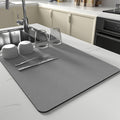 Gray ultra-absorbent kitchen dish mat on white countertop with glassware