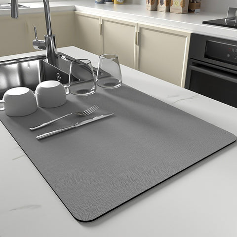 Gray ultra-absorbent kitchen dish mat on white countertop with glassware