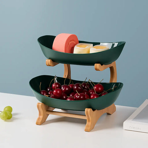 Two-tiered fruit bowl with wooden stand containing cherries and soap on a light blue background