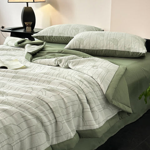 Close-up of soft green cotton gauze quilt and pillowcases on dark wood bed