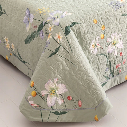 Close-up of green floral cotton quilt showing texture, stitching, and floral print