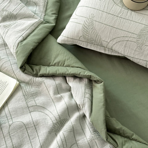 Side view of green bedding with quilt, sheet, and soft cotton texture