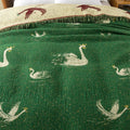 Close-up of swan pattern on green side of reversible cotton tassel blanket