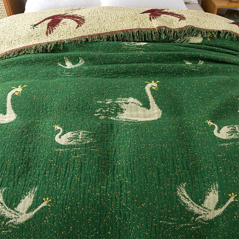 Close-up of swan pattern on green side of reversible cotton tassel blanket