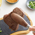 Grilling meat using long wooden handle tongs