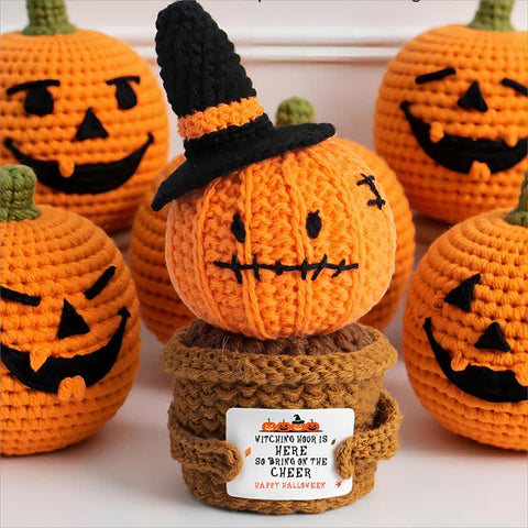 Crochet Halloween pumpkin ornament with witch hat among pumpkin decorations