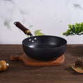 Hammer pattern iron wok pan with wooden handle on wooden cutting board, kitchen decor background