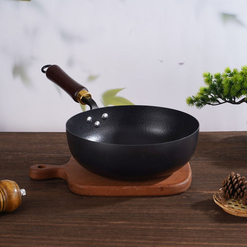 Hammer pattern iron wok pan with wooden handle on wooden cutting board, kitchen decor background