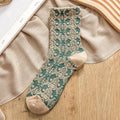 Vintage-style embroidered sock in deep green with beige floral 3D lace design, laid flat on neutral fabric background.