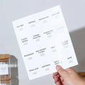 Close-up of a hand holding a minimalist black and white spice label sticker sheet.

