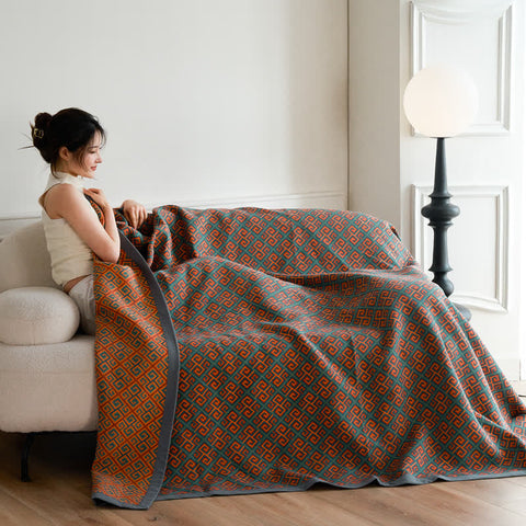 Woman wrapped in Japanese cotton summer quilt sitting on sofa, minimalist room setting
