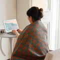 Cozy moment with woman reading laptop wrapped in cotton gauze throw blanket