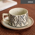 Ceramic cup with geometric pattern on a saucer, placed on a textured surface.