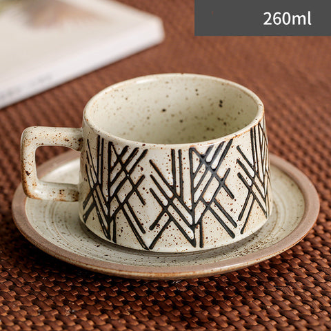 Ceramic cup with geometric pattern on a saucer, placed on a textured surface.