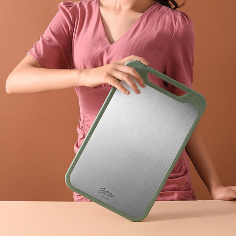 Woman holding green steel chopping board in kitchen