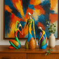 Colorful abstract sculptures on a wooden surface with a vibrant abstract painting in the background.