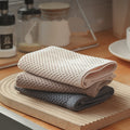 Neutral-toned honeycomb microfiber hand towels stacked on a wooden tray