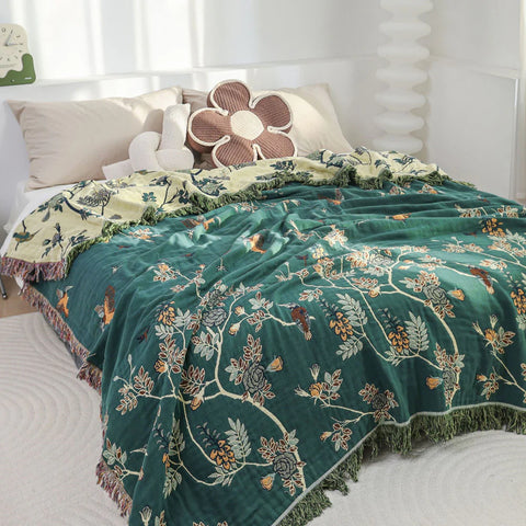 Hummingbird nature-inspired cotton throw blanket in green, reversible with beige, styled as a cozy bed cover.