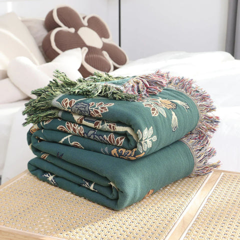 Folded hummingbird nature-inspired cotton throw blanket with fringe trim, reversible design.