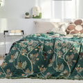 Botanical hummingbird cotton jacquard blanket with floral pattern, used as a reversible bed throw.
