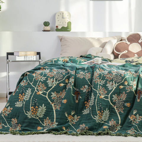 Botanical hummingbird cotton jacquard blanket with floral pattern, used as a reversible bed throw.