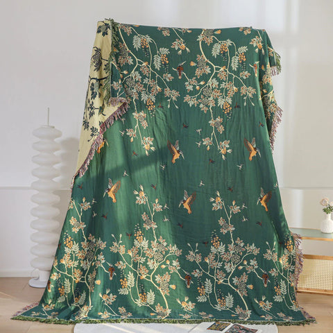 Green floral-patterned blanket draped over a surface with a white curtain in the background.