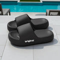 Black slides with 'original' branding on a tiled surface near a pool.