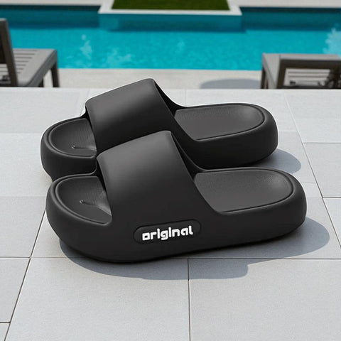 Black slides with 'original' branding on a tiled surface near a pool.