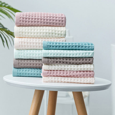 Stack of Japanese waffle cotton bath towels in pastel colors on round stool