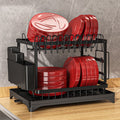 Black dish drying rack with red dishes on a gray marble countertop.