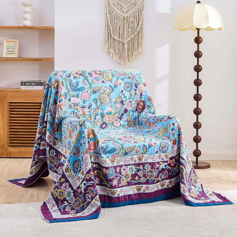 Lavender Meadow Cotton Blanket draped over armchair in cozy, boho-style living room with floor lamp and wooden furniture