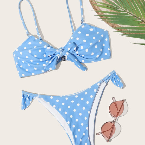 Bikini set flat lay with sunglasses and palm leaf on beige background