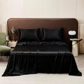 Luxury black satin bed sheets and silky pillowcases styled as twin bedding for a modern hotel bedroom look.