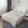 Soft beige cotton boho throw blanket with intricate gray patterns spread elegantly over a cozy bed in a bright, modern bedroom with natural light.