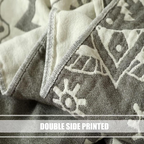 Close-up of double-sided printed beige cotton boho throw blanket showing tribal gray pattern on both sides with detailed stitching.