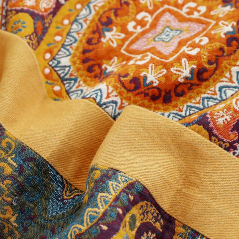 Detail view of mandala pattern on orange cotton quilt with yellow border