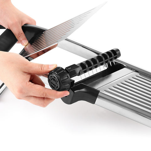 Hand adjusting thickness dial on stainless mandoline slicer
