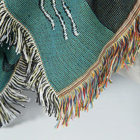 Detailed view of fringed edge on ocean-themed tapestry blanket