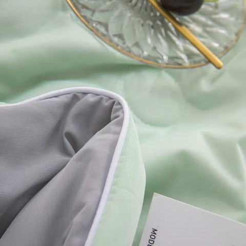 Close-up of mint green ice silk quilt with gray fabric border and detailed texture