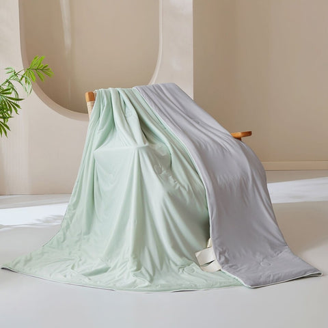 Soft mint green ice silk quilt with smooth fabric detail and folded corner showing light grey lining
