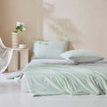 Mint green ice silk quilt set on neatly made bed with matching pillows in modern bedroom