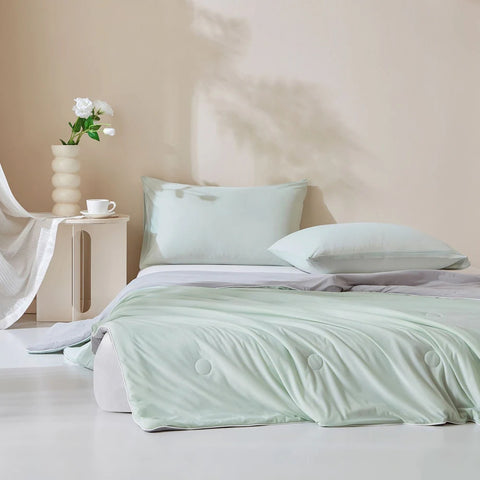 Mint green ice silk quilt set on neatly made bed with matching pillows in modern bedroom